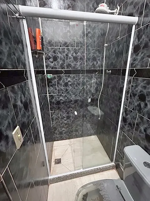 Box de correr em vidro temperado com perfil branco em banheiro de revestimento escuro